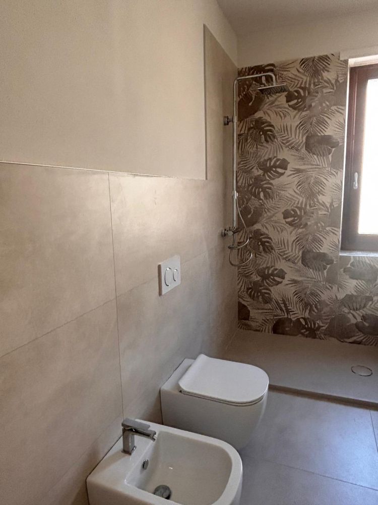 Bagno rifatto con doccia a filo pavimento e rivestimento decorativo